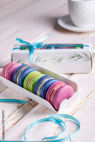 Colorful macaroons in a box on a light wooden table close-up