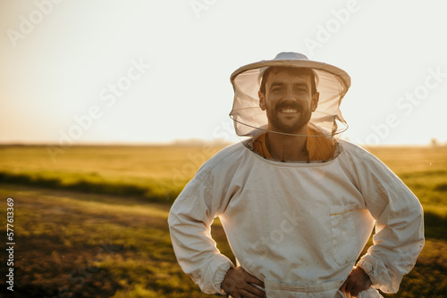 Portrait of a handsome beekeeper in a protective uniform standing outdoors in the field. Copy space photo
