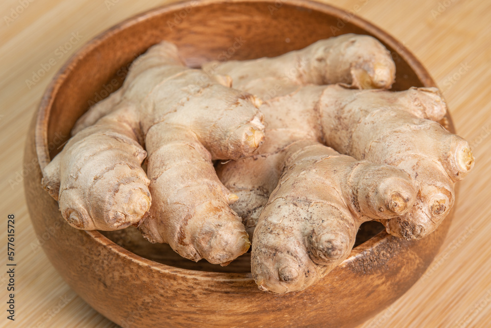 Fresh whole ginger root on wooden background close up. Spices and herbs seasoning for cooking. Medicinal herbs. Use of slice ginger in aromatherapy. High content of essential oils in the plant