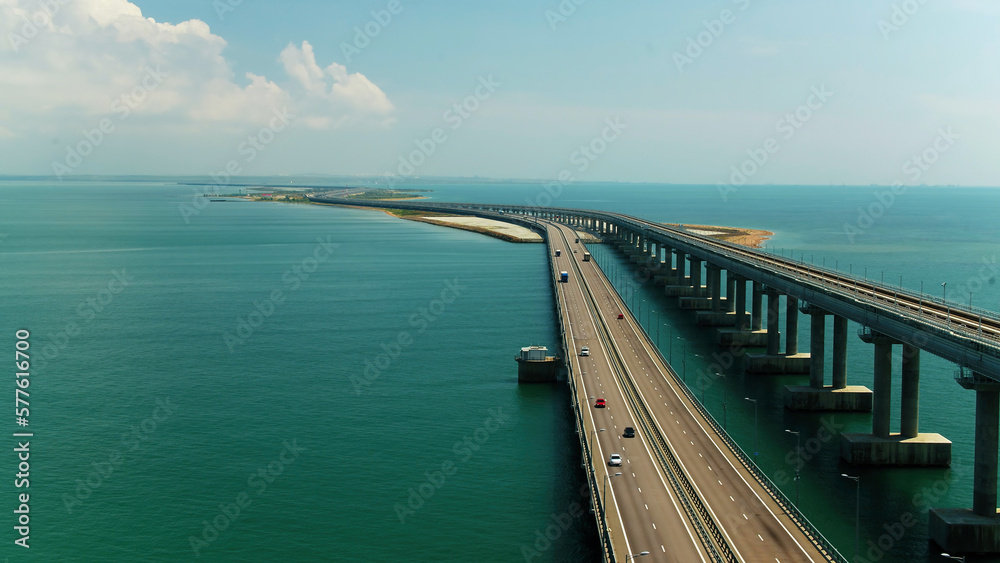 Aerial view of a bridge and a river or the sea. Shot. Long narrow bridge across the cities on a blue cloudy sky background.