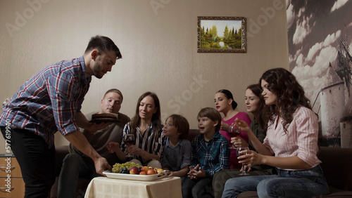 Big happy family sitting on a couch by the small table with fruit plate. Stock. Celebration at home with children.