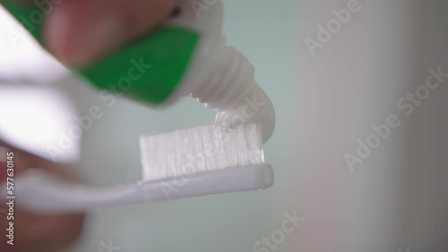Squeezing white toothpaste from a tube onto toothbrush. Brushing her teeth, morning and evening procedures