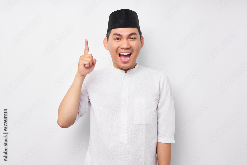 Excited Young Asian Muslim man in Arabic costume having creative idea, pointing his finger up at free space for advertisement isolated on white background. People religious Islamic lifestyle concept Excited Young Asian Muslim man in Arabic costume having creative idea, pointing his finger up at free space for advertisement isolated on white background. People religious Islamic lifestyle concept