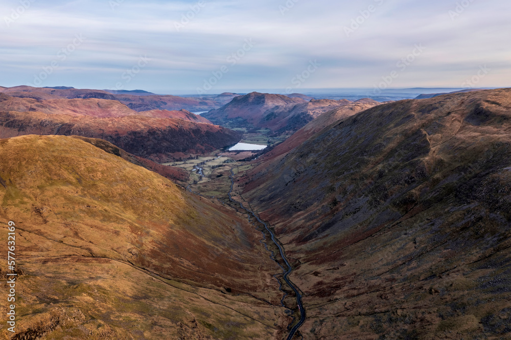 Beautiful aerial drone landscape image of sunrise Winter view from Red Screes in Lake District looking towards Brothers Water and Ullswater in the distance over mountain peaks