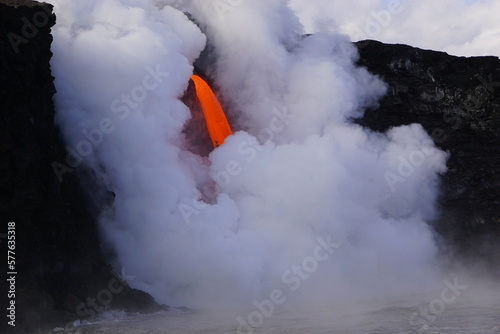 Hot lava falling down from high cliff into ocean