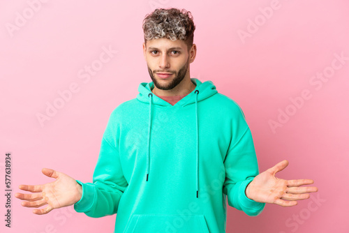 Young handsome caucasian man isolated on pink background having doubts © luismolinero