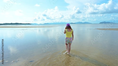 Beautiful view of Asian woman walking on the sand beach and looking at the sea. People with a nature concept.