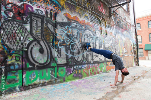 Flexible and strong male does back bend against a graffiti wall in Baltimore, Maryland photo