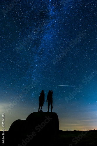 A couple stands under the milky way and metor shower photo