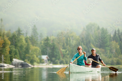 Young couple canoeing with their dog on a lake in summer. photo