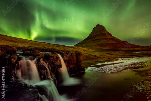 The Aurora exploding in green over a waterfall.