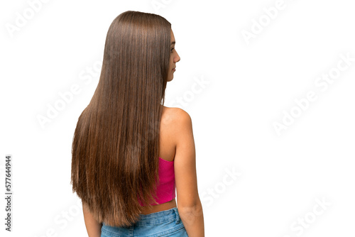 Teenager caucasian girl over isolated background in back position and looking side