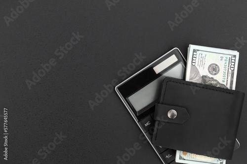 Wallet with dollar bills and calculator on black background. Top view. Calculating money and salary. Copy space.