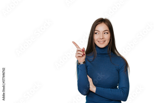 Beautiful European girl with long loose hair in a blue sweater points by  her index finger to the side, to an empty place, on transparent background looks at imaginary object. Promo, mockup, discount.