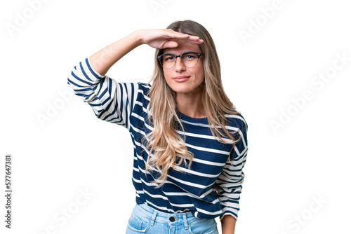 Young Uruguayan woman over isolated background looking far away with hand to look something