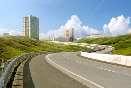 Asphalt road with green grass and cityscape