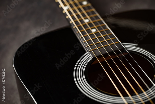 Guitar black, polished smooth soundboard, stretched six strings, copper frets on neck, close-up selective focus
