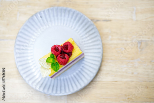 Rainbow raspberry cheesecake on white plate on wooden table