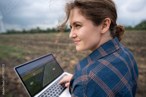 Farmer with laptop on the field. Wind turbines on a horizon. Smart sustainable farming and agriculture digitalization	
 photo