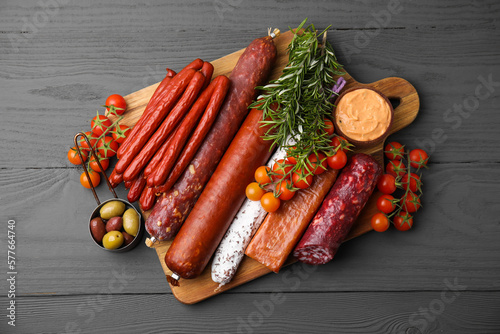 Different types of tasty sausages on grey wooden table, flat lay