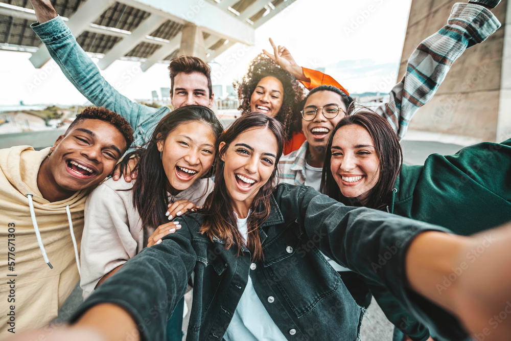 Fototapeta premium Happy multi ethnic young people taking selfie photo with smart mobile phone outside - Life style concept with guys and girls having fun hanging out on city street - Youth community concept
