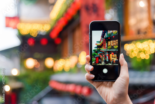Traveller tourist hand holding smartphone while taking a photograph of jiufen Culture Village Taipei, Taiwan (Letters With Means Tea shop)