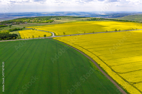 Aerial shot of fields with a tractor traces on the agricultural field sowing. Green and yellow contrast.