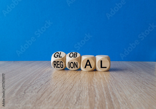 Regional or global symbol. Turned wooden cubes and changes the word 'regional' to 'global'. Beautiful wooden table, blue background. Business and regional or global concept. Copy space.