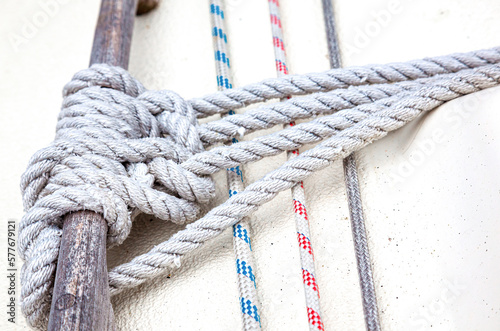 Ropes tied and stretched to a wooden handrail on the deck of a yacht, close-up.