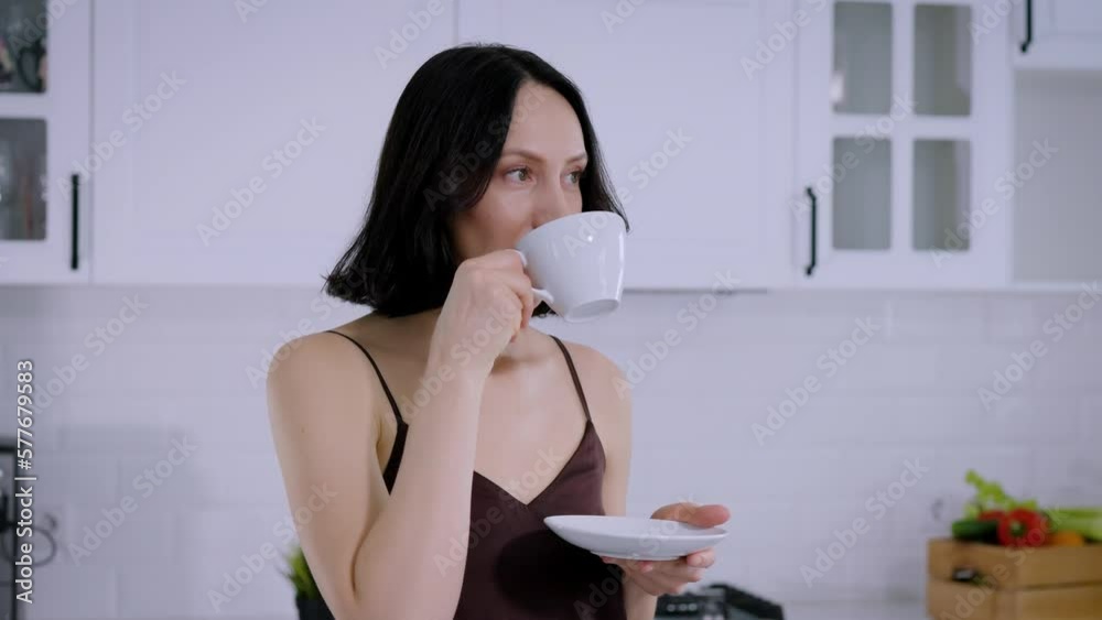 Close-up middle-aged brunette woman enjoy coffee or tea in the kitchen Close-up middle-aged brunette woman enjoy coffee or tea in the kitchen