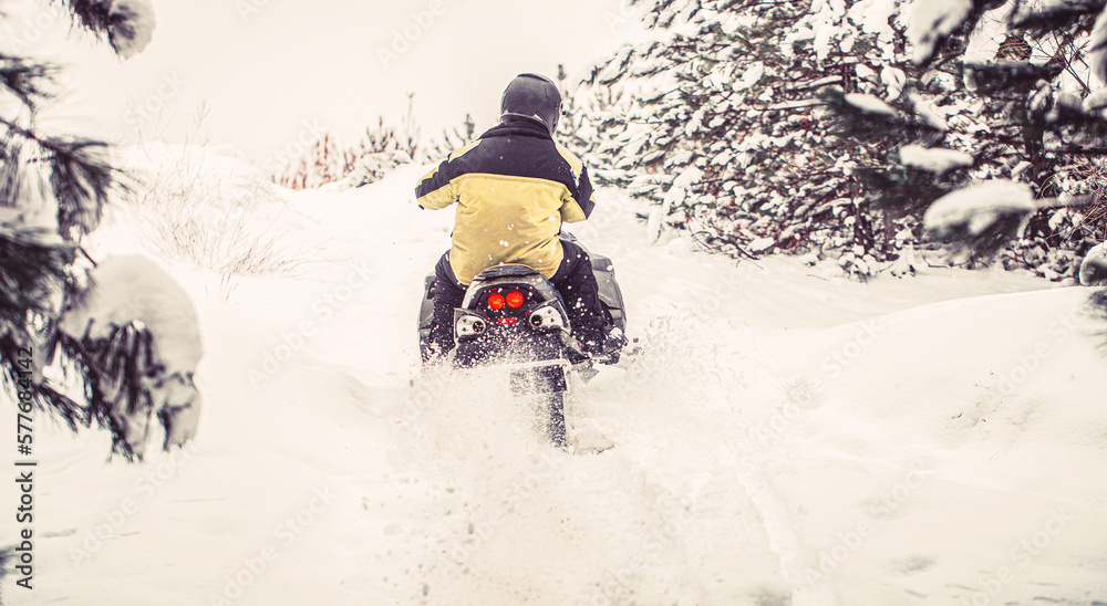 Athlete rides a snowmobile in the mountains. Snowmobile in snow. Concept winter sports. Man is riding snowmobile in mountains. Pilot on a sports snowmobile in a mountain forest