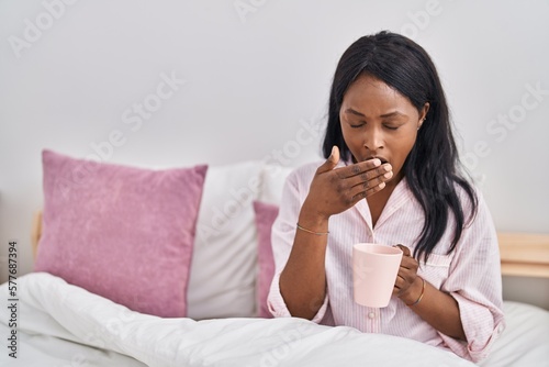 Young african american woman drinking coffee waking up at bedroom