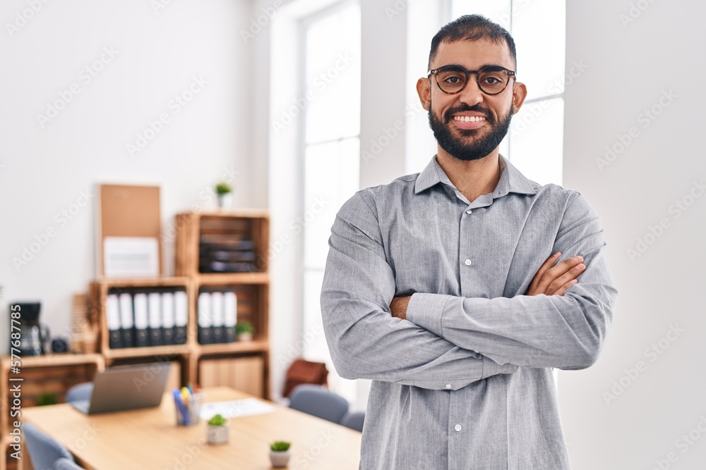 Young hispanic man business worker smiling confident standing with arms crossed gesture at office