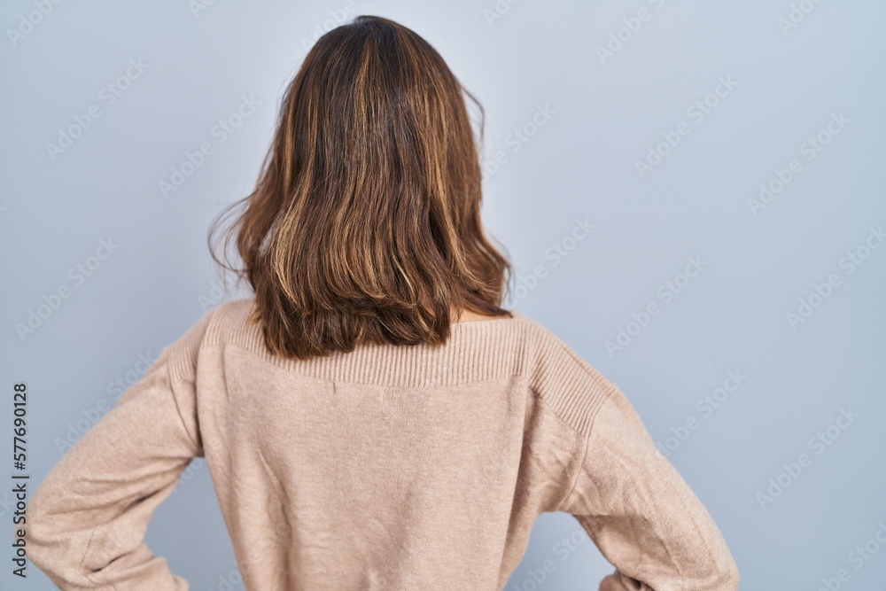 Young woman standing over isolated background standing backwards looking away with arms on body Young woman standing over isolated background standing backwards looking away with arms on body