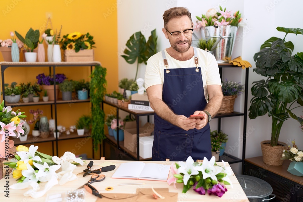 Middle age man florist make photo to flowers by smartphone at flower shop Middle age man florist make photo to flowers by smartphone at flower shop