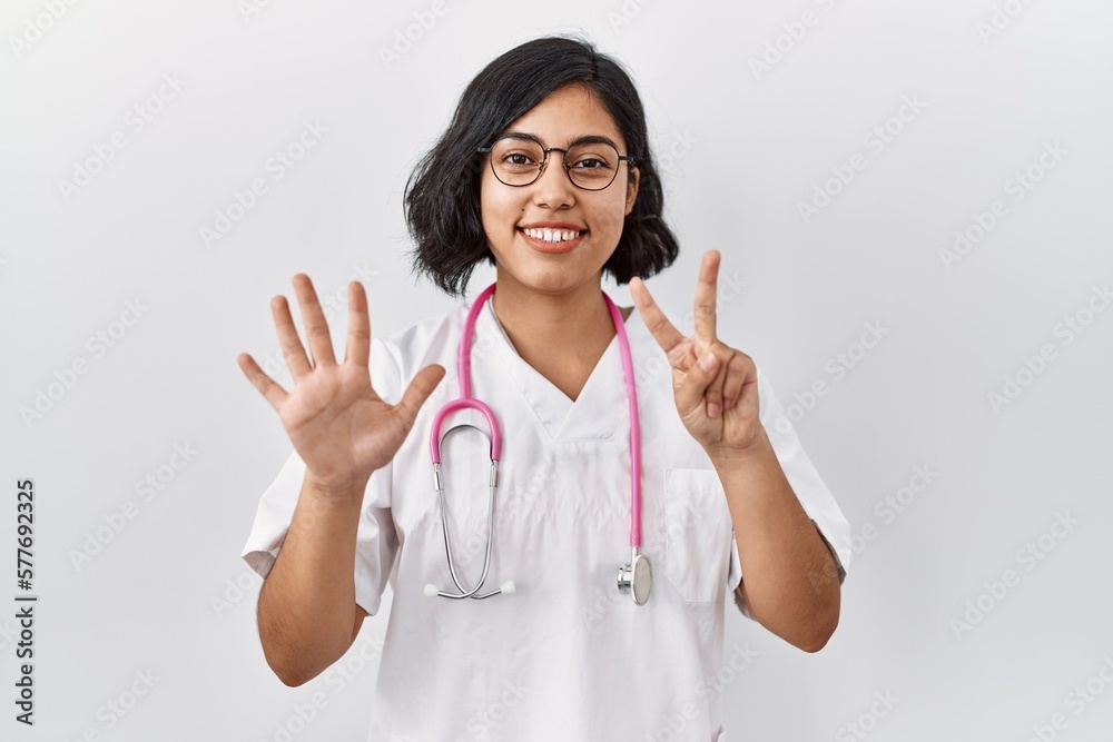 Young hispanic doctor woman wearing stethoscope over isolated background showing and pointing up with fingers number seven while smiling confident and happy. Young hispanic doctor woman wearing stethoscope over isolated background showing and pointing up with fingers number seven while smiling confident and happy.