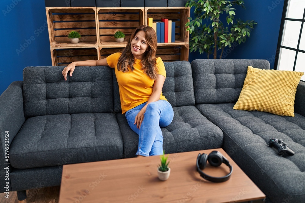 Obraz premium Young latin woman smiling confident sitting on sofa at home