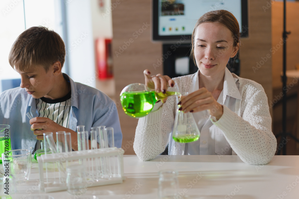 Caucasian teacher teaching caucasian kid boy with chemical test tube Caucasian teacher teaching caucasian kid boy with chemical test tube