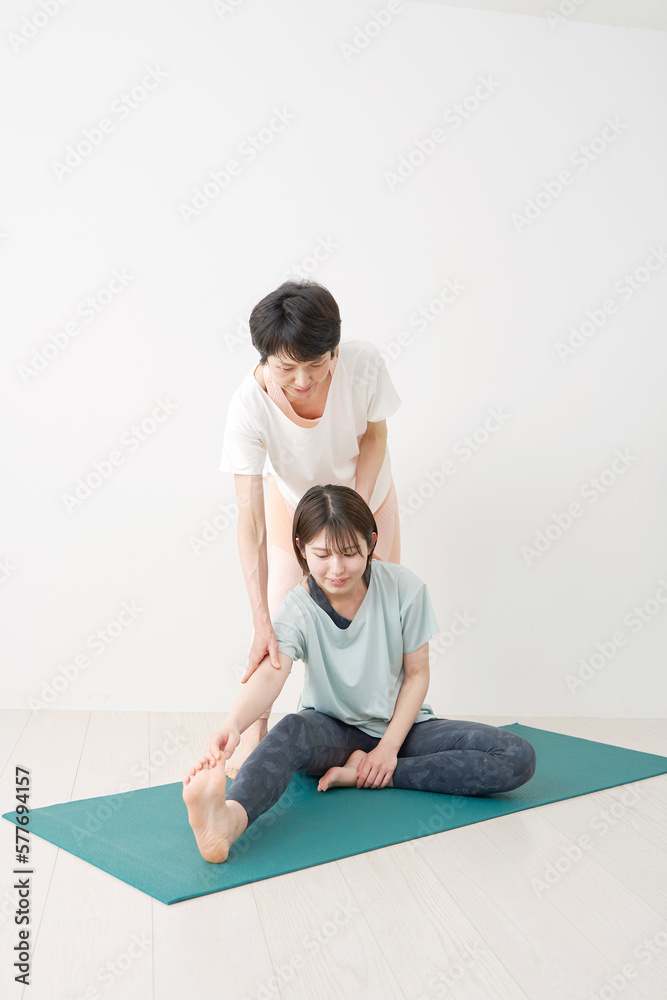 インストラクターと柔軟運動をする女性
