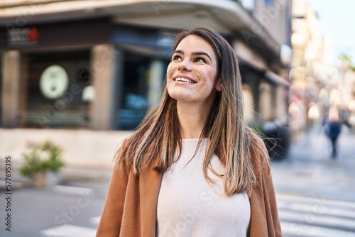 Young beautiful hispanic woman smiling confident looking to the sky at street