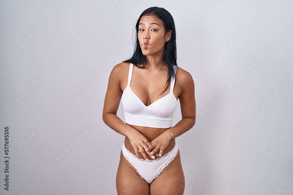 Fototapeta premium Hispanic woman wearing lingerie making fish face with lips, crazy and comical gesture. funny expression.