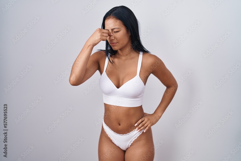 Hispanic woman wearing lingerie tired rubbing nose and eyes feeling fatigue and headache. stress and frustration concept. Hispanic woman wearing lingerie tired rubbing nose and eyes feeling fatigue and headache. stress and frustration concept.