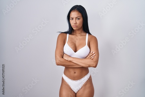 Hispanic woman wearing lingerie skeptic and nervous, disapproving expression on face with crossed arms. negative person.