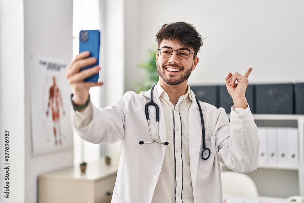 Hispanic man with beard working on online appointment smiling happy pointing with hand and finger to the side
