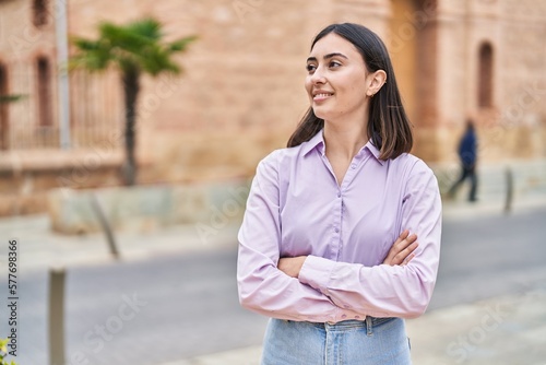 Young hispanic woman smiling confident standing with arms crossed gesture at street