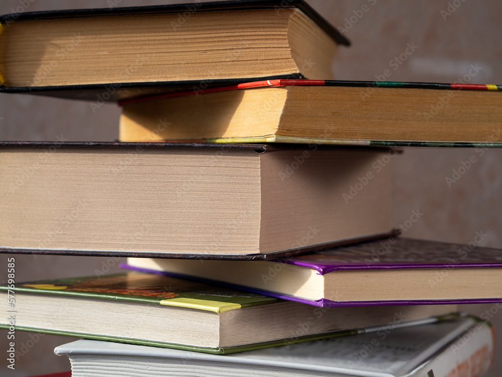 Fototapeta premium Books of different thicknesses in a stack are shifted relative to each other. Close-up. The concept of reading, libraries, scientific work, education.