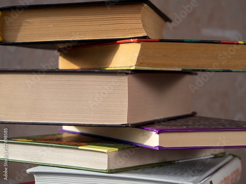 Books of different thicknesses in a stack are shifted relative to each other. Close-up. The concept of reading, libraries, scientific work, education.