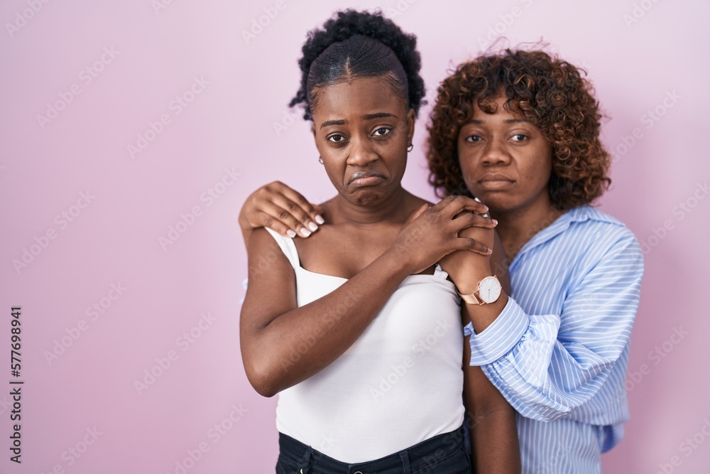 Two african women standing over pink background depressed and worry for distress, crying angry and afraid. sad expression. Two african women standing over pink background depressed and worry for distress, crying angry and afraid. sad expression.