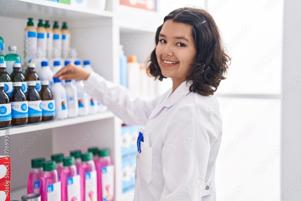 Young woman pharmacist holding medication bottle at pharmacy