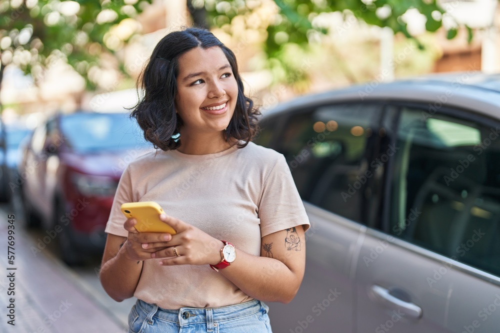 Fototapeta premium Young woman smiling confident using smartphone at street